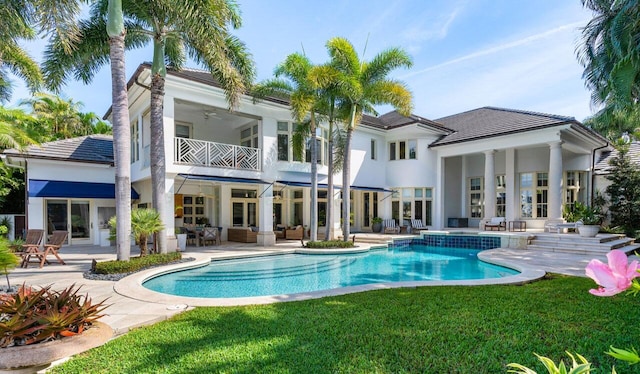 back of house featuring a lawn, a ceiling fan, a patio area, a balcony, and an outdoor living space