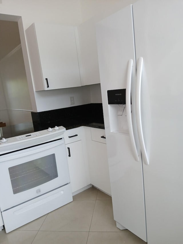 kitchen with white appliances, white cabinetry, and light tile patterned flooring