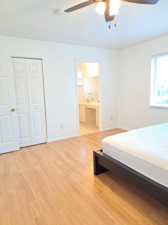 bedroom with light wood-type flooring, a closet, ceiling fan, and connected bathroom