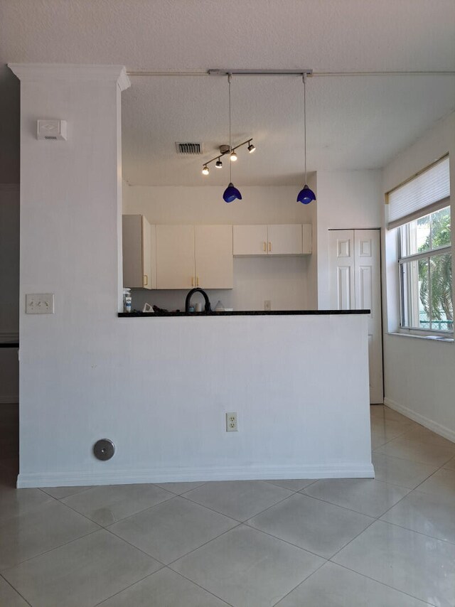 kitchen featuring track lighting, white cabinetry, a textured ceiling, and light tile patterned flooring