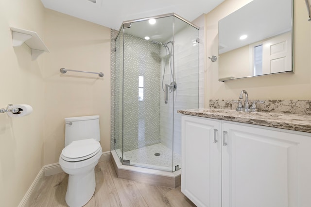 bathroom with hardwood / wood-style floors, a shower with shower door, vanity, and toilet