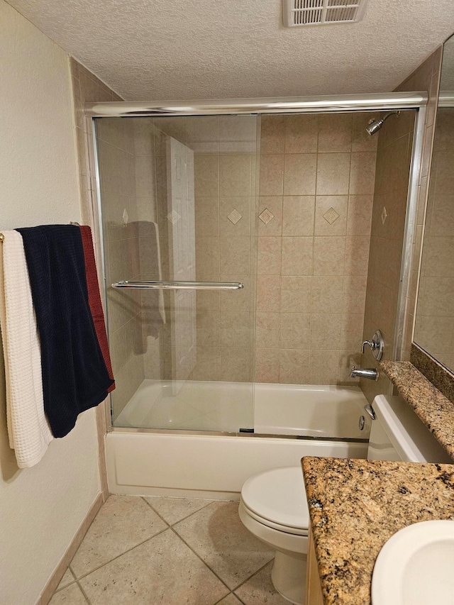 full bathroom with a textured ceiling, vanity, combined bath / shower with glass door, toilet, and tile patterned floors