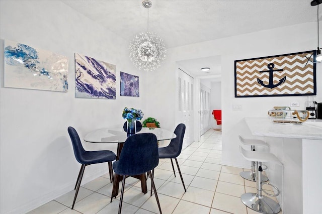 dining room featuring a notable chandelier, a textured ceiling, and light tile patterned floors