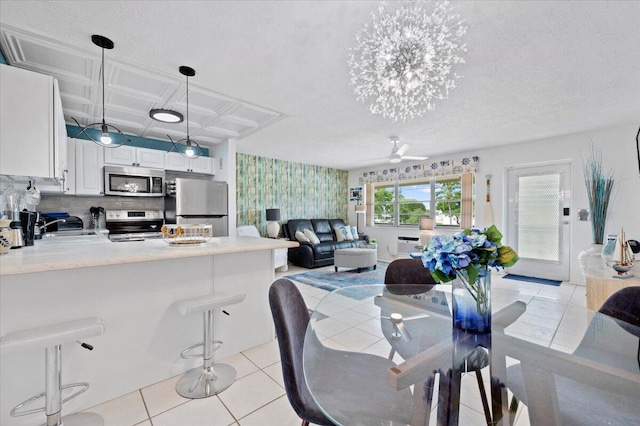 tiled dining area featuring sink, ceiling fan with notable chandelier, and a textured ceiling