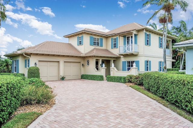 view of front of home featuring decorative driveway, a balcony, an attached garage, and stucco siding