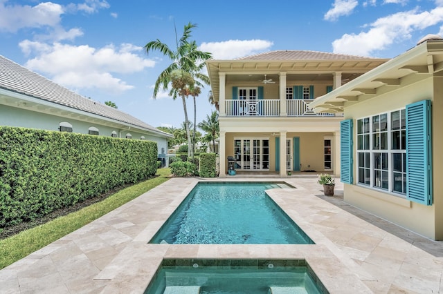 back of house with french doors, a balcony, a patio area, an in ground hot tub, and a ceiling fan