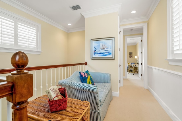 sitting room with a wealth of natural light, visible vents, light colored carpet, and ornamental molding