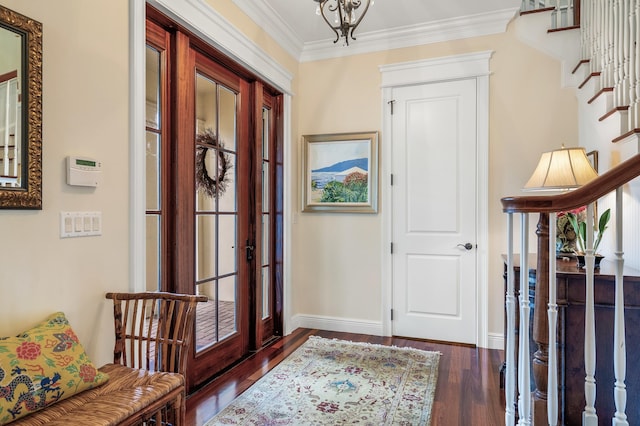 entryway featuring ornamental molding, wood finished floors, baseboards, a chandelier, and stairs