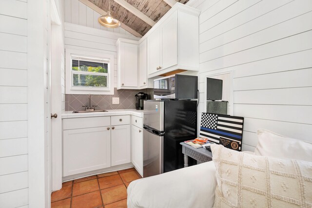 kitchen with white cabinets, wood ceiling, sink, wood walls, and vaulted ceiling with beams