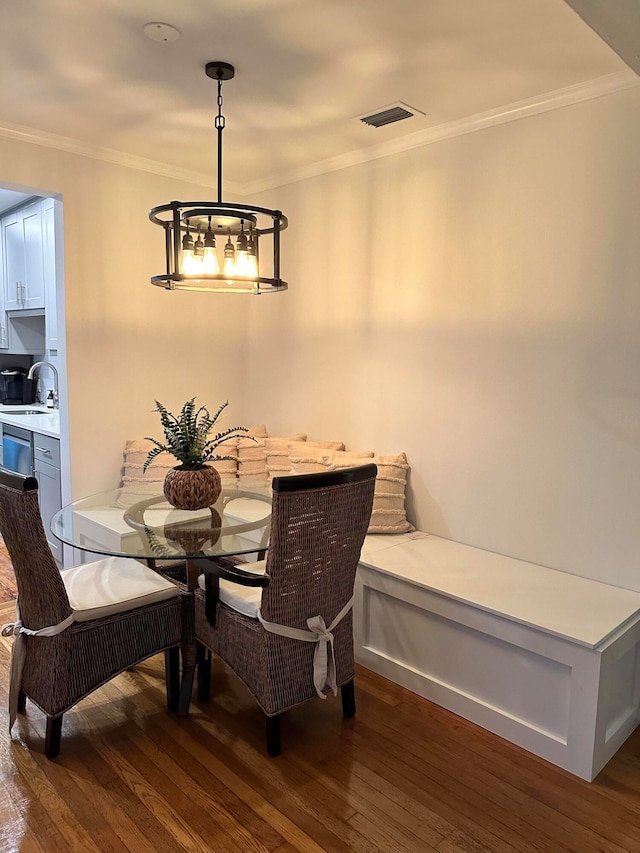 dining space featuring ornamental molding, sink, a chandelier, and dark hardwood / wood-style flooring