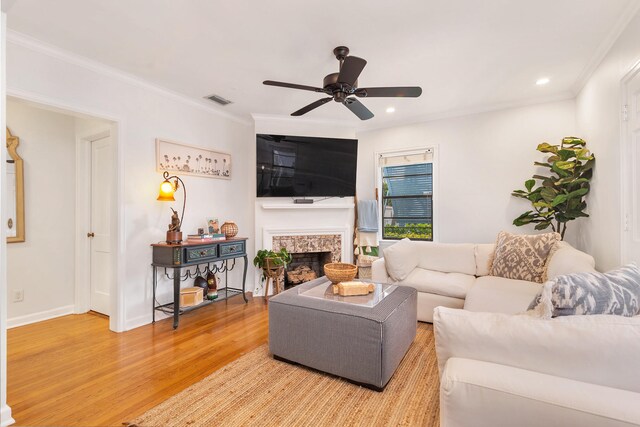 living room featuring ceiling fan, ornamental molding, and light wood-type flooring