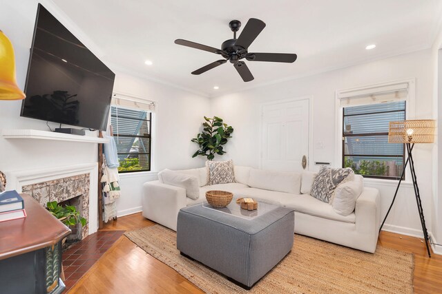 living room featuring hardwood / wood-style flooring, ceiling fan, and a stone fireplace