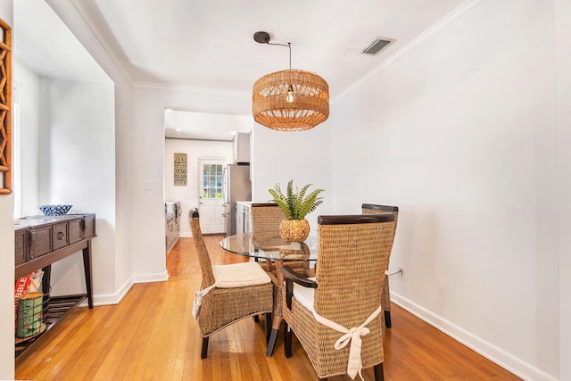 dining space with crown molding and light hardwood / wood-style flooring