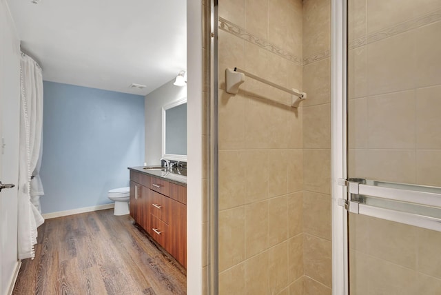 bathroom with vanity, toilet, hardwood / wood-style floors, and a shower with shower door