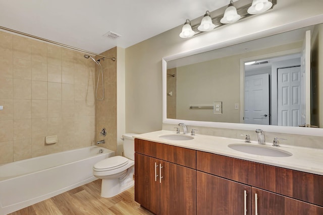 full bathroom featuring tiled shower / bath combo, vanity, toilet, and wood-type flooring