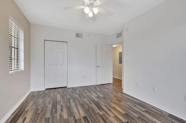 unfurnished bedroom featuring electric panel, dark wood-type flooring, ceiling fan, and a closet