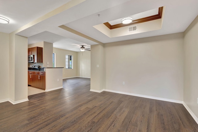 empty room with ornamental molding, a raised ceiling, ceiling fan, and dark hardwood / wood-style floors