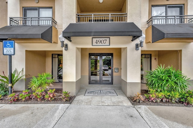 property entrance with a balcony and french doors