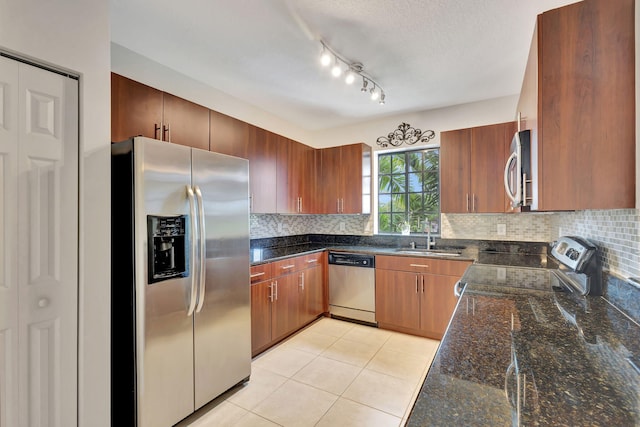 kitchen with stainless steel appliances, dark stone countertops, sink, and decorative backsplash