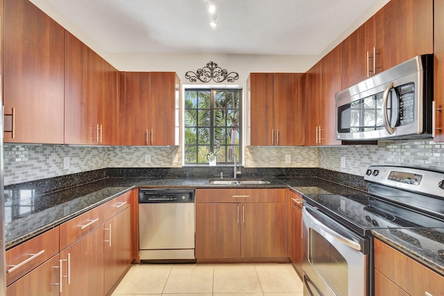 kitchen with dark stone countertops, appliances with stainless steel finishes, tasteful backsplash, and sink