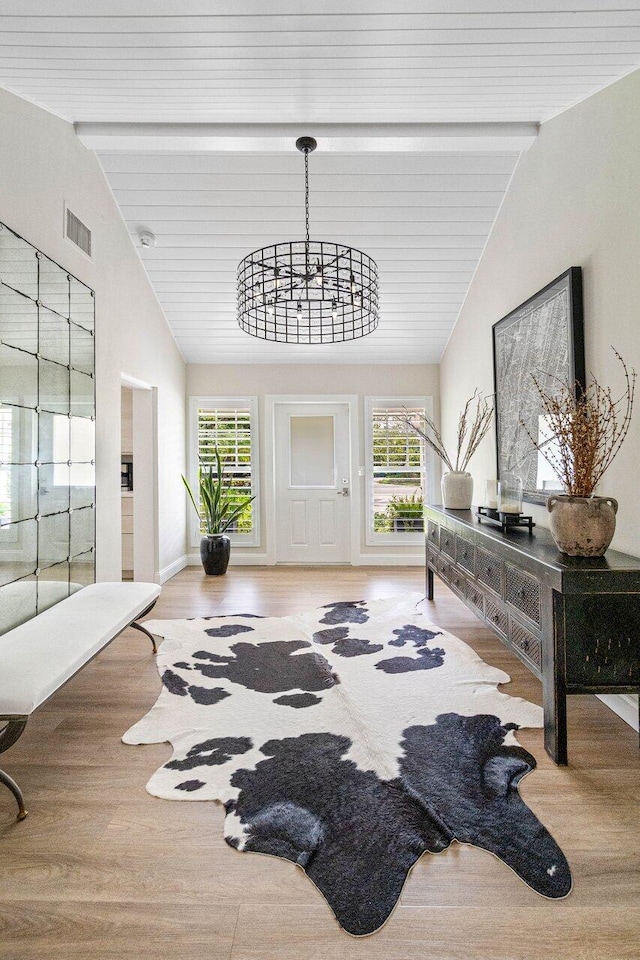 entryway featuring lofted ceiling with beams, a healthy amount of sunlight, and wood finished floors