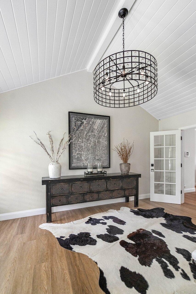 interior space featuring vaulted ceiling with beams, a notable chandelier, and light hardwood / wood-style floors