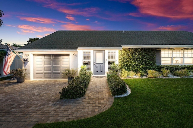 ranch-style home with a garage and a lawn