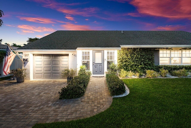 ranch-style home with decorative driveway, a garage, stucco siding, and a front yard