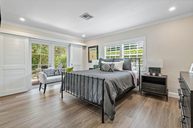 bedroom with hardwood / wood-style floors, multiple windows, and ornamental molding