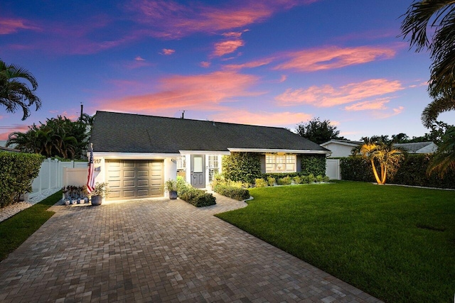 single story home featuring a garage and a yard