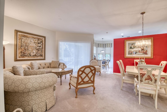 living room featuring light carpet, baseboards, and a notable chandelier