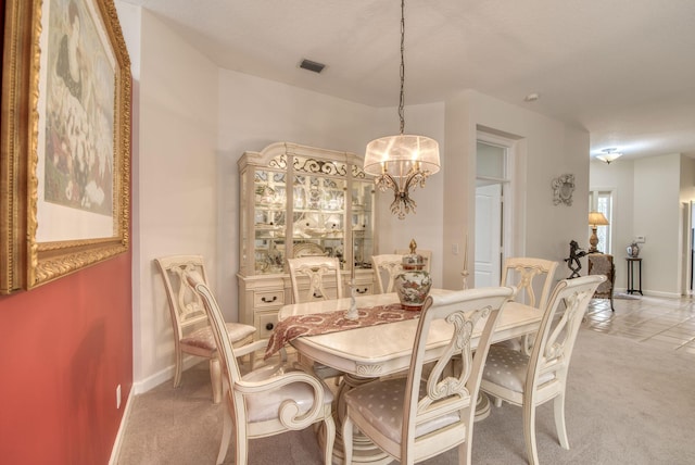 dining room featuring baseboards, a chandelier, visible vents, and light colored carpet