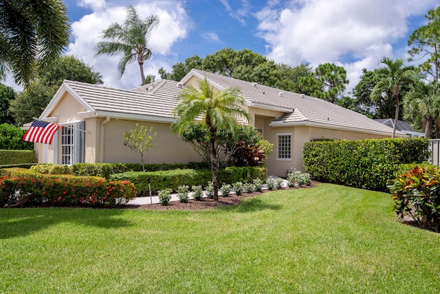 exterior space with a tile roof, a lawn, and stucco siding