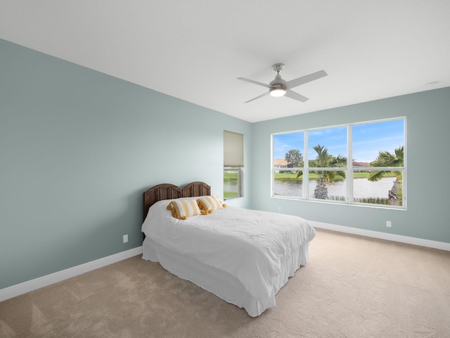 bedroom featuring carpet flooring, ceiling fan, and a water view