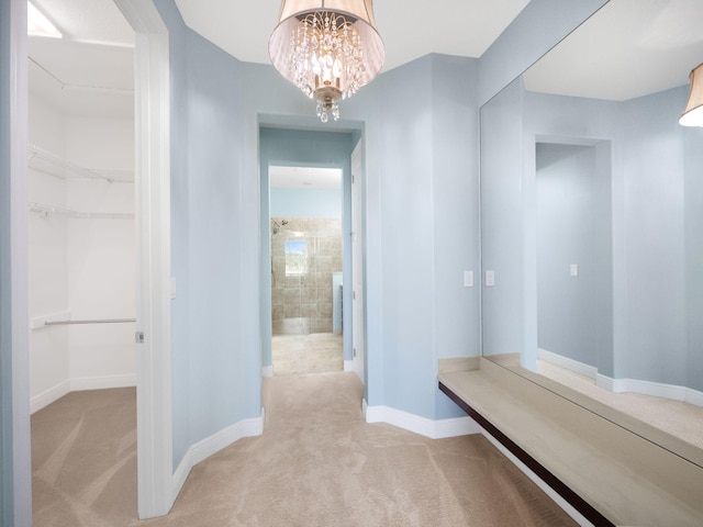 hallway featuring light colored carpet and an inviting chandelier