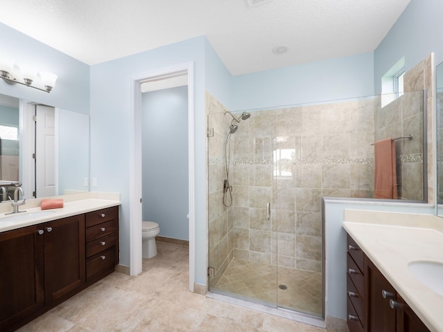 bathroom with vanity, toilet, a shower with shower door, and a textured ceiling