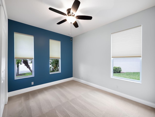 carpeted spare room featuring ceiling fan