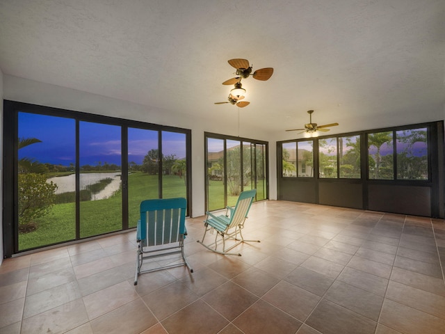 unfurnished sunroom with a water view and ceiling fan