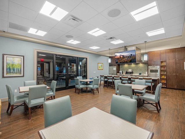 dining room featuring dark wood-type flooring and a drop ceiling