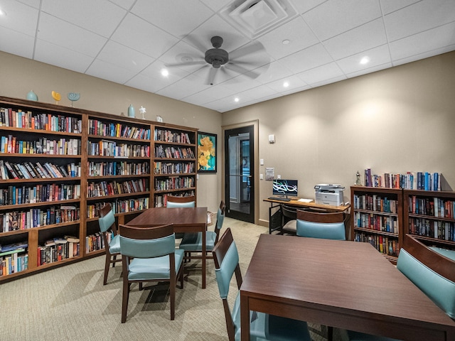 office space featuring light carpet, ceiling fan, and a drop ceiling