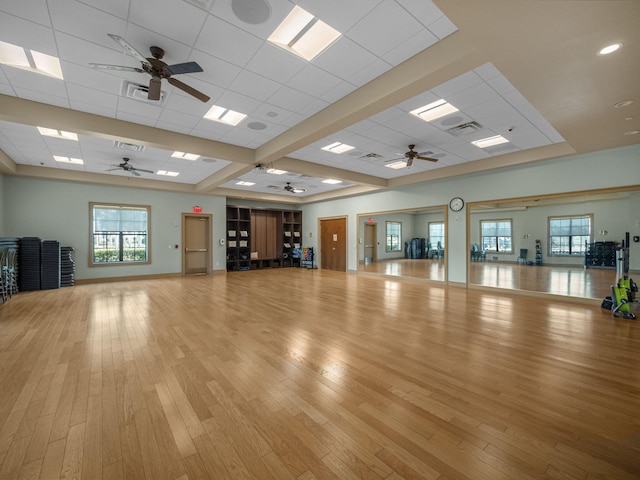 exercise room with light wood-type flooring, ceiling fan, and a drop ceiling