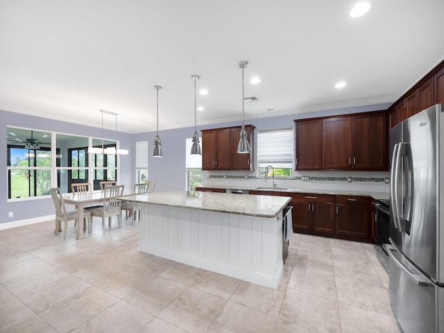 kitchen featuring decorative light fixtures, stainless steel fridge, light stone countertops, and sink