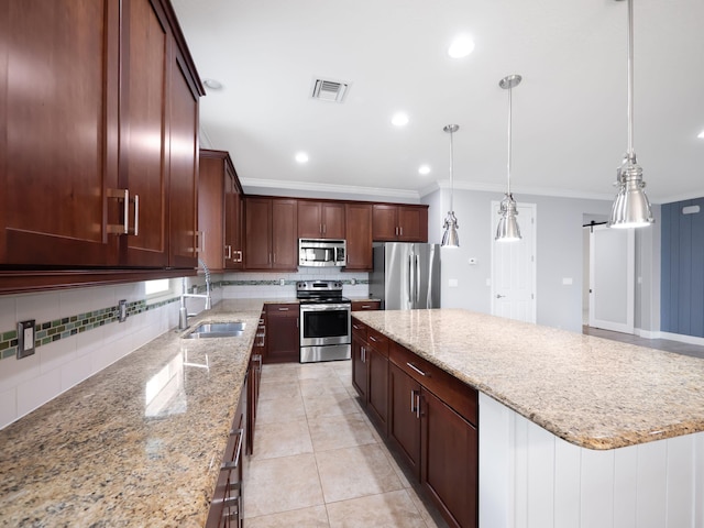 kitchen with pendant lighting, appliances with stainless steel finishes, a center island, sink, and light stone counters