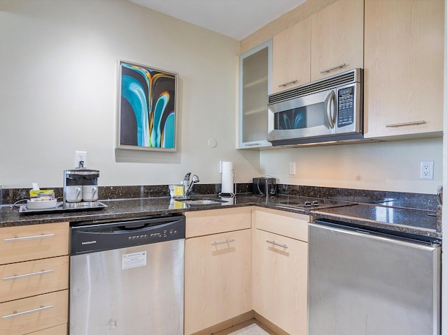 kitchen featuring light brown cabinets, appliances with stainless steel finishes, sink, and dark stone counters