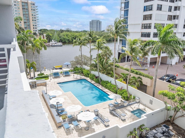 view of pool with a patio, a water view, and a community hot tub