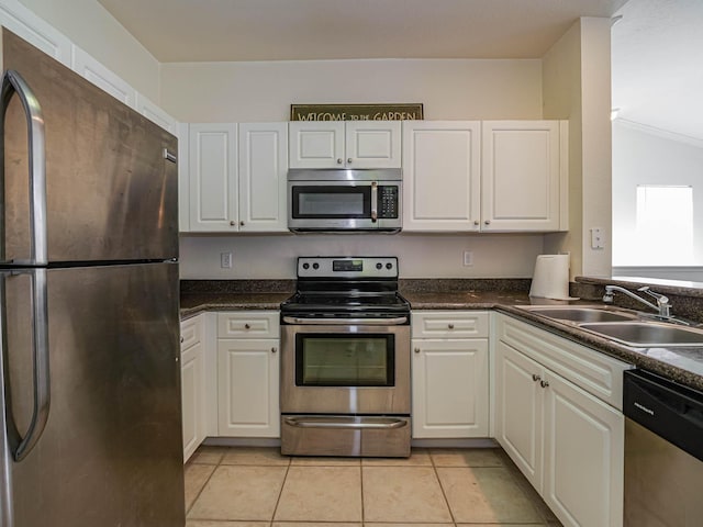 kitchen featuring white cabinetry, sink, lofted ceiling, light tile patterned flooring, and appliances with stainless steel finishes