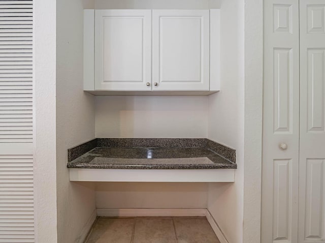 interior space featuring dark stone countertops, white cabinetry, and light tile patterned floors