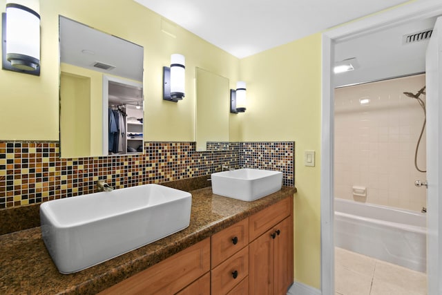 bathroom with tile patterned floors, tiled shower / bath combo, decorative backsplash, and vanity