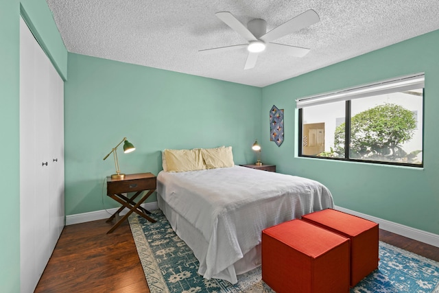 bedroom featuring a textured ceiling, dark wood-type flooring, ceiling fan, and a closet