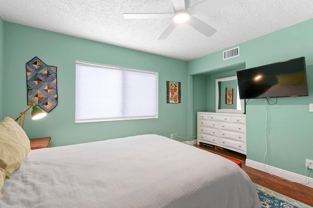 bedroom featuring dark wood-type flooring, a textured ceiling, and ceiling fan